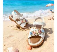 Ein Muss-haben Modeartikel im Jahr 2025: Ein Paar flache Sandalen für Kinder im Alter von 3 bis 12 Jahren. Die weiße Lederblume ist leicht an- und aus